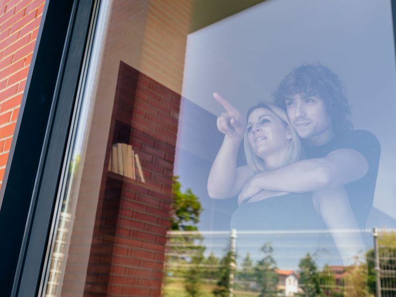 Couple looking at the garden through the window Couple looking at the garden of their new house through the window