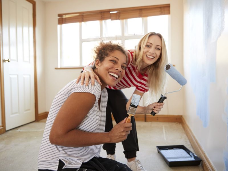 Portrait Of Two Women Decorating Room In New Home Painting Wall Portrait Of Two Women Decorating Room In New Home Painting Wall